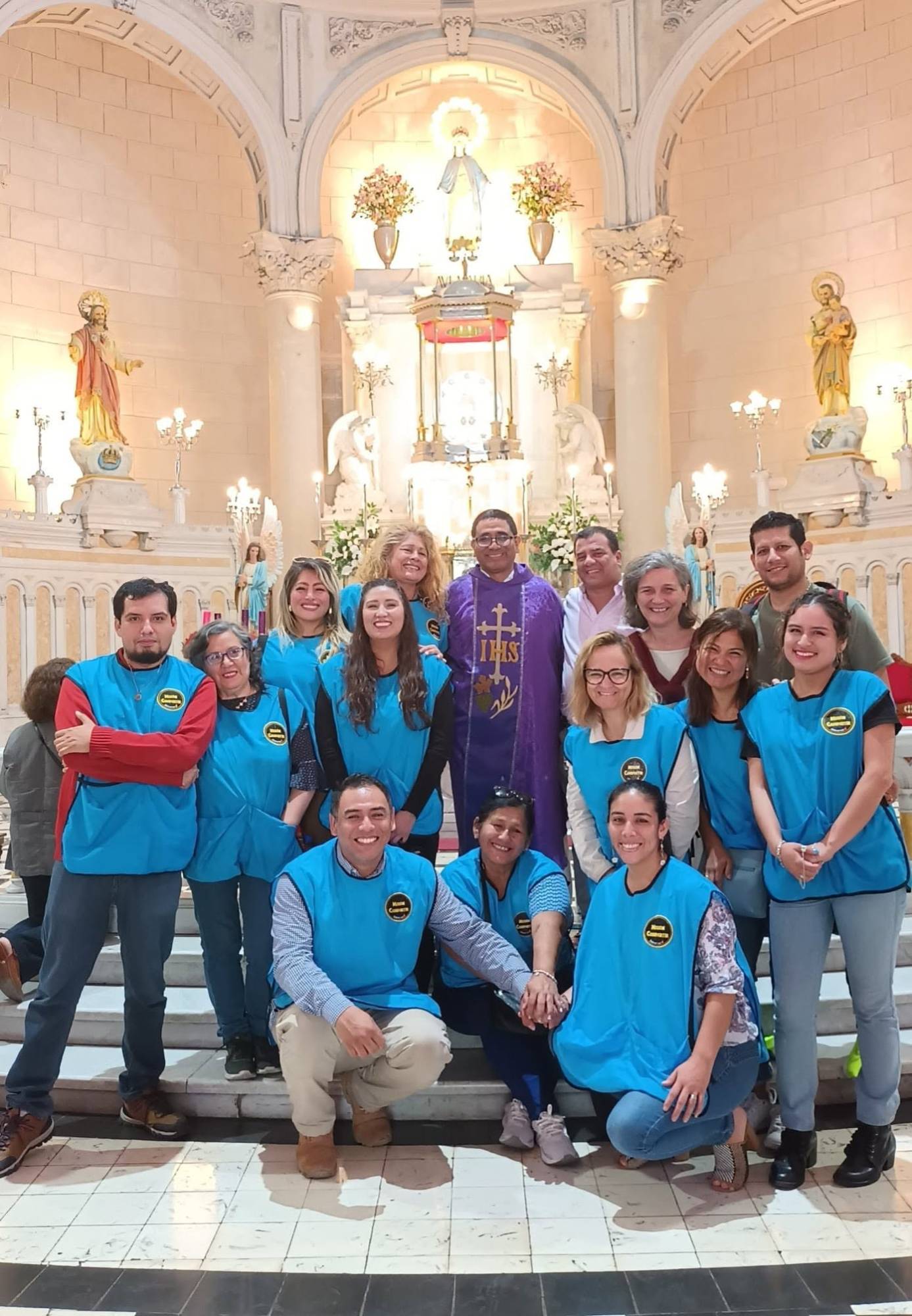 Voluntarios de Misión Compartir con sus chalecos azules, reunidos en una iglesia